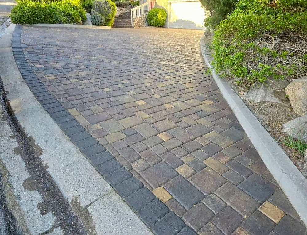 Paved driveway with a curved design, featuring alternating dark and light bricks.